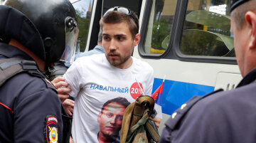 Riot police detain a man dressed in a t-shirt depicting opposition leader Alexei Navalny, during the
