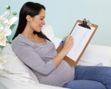 Pregnant woman sitting in a chair writing baby names