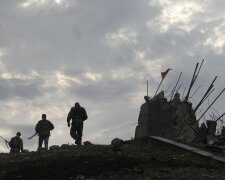 Pro-Russian separatists walk at a destroyed war memorial on Savur-Mohyla, a hill east of the city of