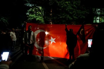 People with Turkish flags stand in front of the Turkish embassy in Berlin