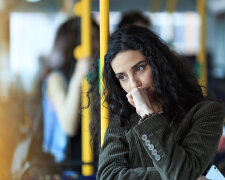 Pensive young woman traveling and holding smart phone