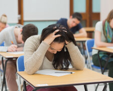 Stressed student sitting in a classroom at a table while doing a test