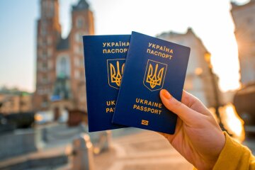 Female hands holding Ukrainian abroad passports on the Krakow city center background