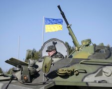 A Ukrainian soldier rides on an armoured personnel carrier during a military exercise near the villa