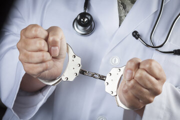 Female Doctor or Nurse In Handcuffs Wearing Lab Coat and Stethoscope.