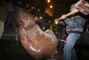 A man holds a sledgehammer as he smashes a statue of Soviet state founder Vladimir Lenin, which was 