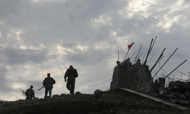 Pro-Russian separatists walk at a destroyed war memorial on Savur-Mohyla, a hill east of the city of