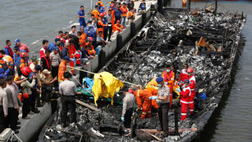 Police and rescue workers search a boat for victims at Muara Angke port in Jakarta, Indonesia