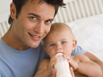 Father bottle feeding baby