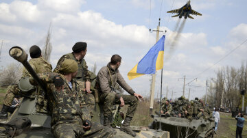 Ukrainian servicemen look at a Ukrainian military jet fly above them in Kramatorsk