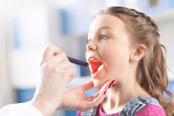 Cropped shot of woman doctor checking throat of little girl