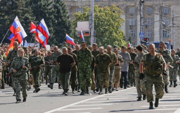 Armed pro-Russian separatists escort a column of Ukrainian prisoners of war as they walk across cent