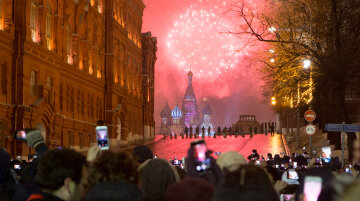 People watch as fireworks explode over the Kremlin standing at Red Square blocked by police during New Year celebrations in Moscow, Russia, Sunday, Jan. 1, 2017. New Year's Eve is Russia's major gift-giving holiday, and big Russian cities were awash in festive lights and decorations. (AP Photo/Alexander Zemlianichenko Jr)