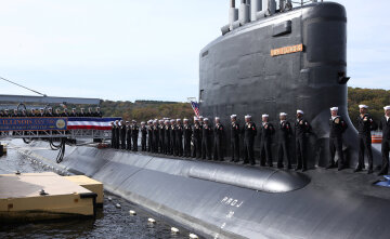 Crew members stand on the topside of the submarine during the commissioning of the USS Illinois, the