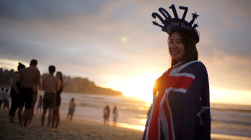 A beachgoers drapes herself in the Australian flag and wears 2017 headwear on Sydney's Bondi Beach to welcome the first sunrise of the new year in Australia's largest city, January 1, 2017.    REUTERS/Jason Reed