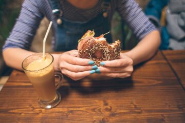Stocksy-woman-eating-bagel-CACTUS-Blai-Baules