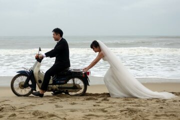 A Vietnamese bride is seen pushing the groom on a scooter during a photo shoot for their wedding in An Bang Beach outside Hoi An in Vietnam December 11, 2016. REUTERS/Stringer