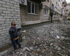 A boy plays near a residential building, damaged by what locals say was overnight shelling by Ukrain