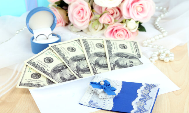 Dollar bills in envelope as gift at wedding on wooden table close-up