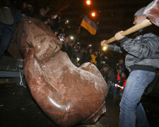 A man holds a sledgehammer as he smashes a statue of Soviet state founder Vladimir Lenin, which was 