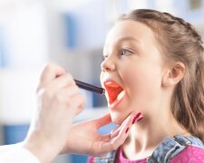 Cropped shot of woman doctor checking throat of little girl