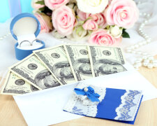 Dollar bills in envelope as gift at wedding on wooden table close-up