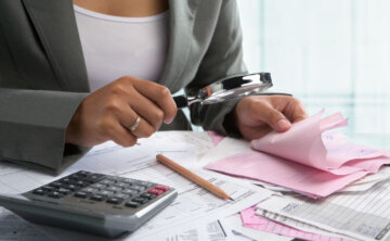 Businesswoman checking bills using magnifying glass