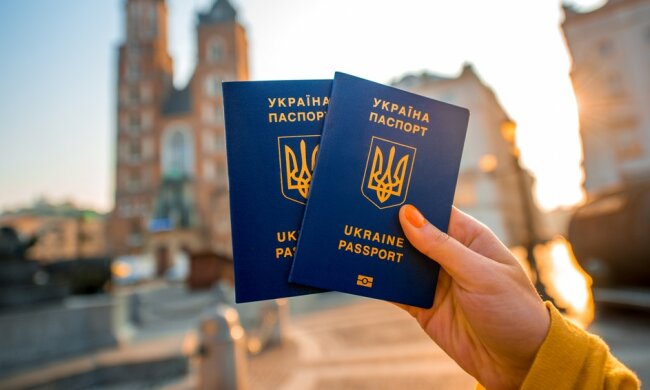 Female hands holding Ukrainian abroad passports on the Krakow city center background