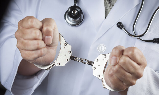 Female Doctor or Nurse In Handcuffs Wearing Lab Coat and Stethoscope.