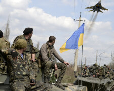 Ukrainian servicemen look at a Ukrainian military jet fly above them in Kramatorsk