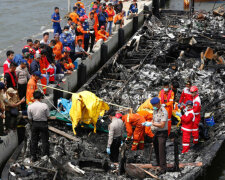 Police and rescue workers search a boat for victims at Muara Angke port in Jakarta, Indonesia