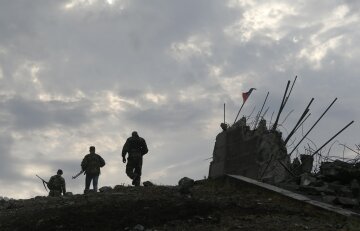 Pro-Russian separatists walk at a destroyed war memorial on Savur-Mohyla, a hill east of the city of