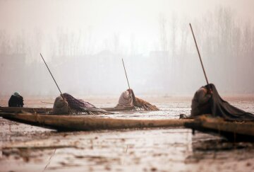 Kashmiri fishermen cover their heads and part of their boats with blankets and straw as they wait to catch fish in the waters of the Anchar Lake on a cold day in Srinagar, December 20, 2016. REUTERS/Danish Ismail