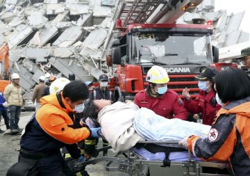 Rescue personnel help a victim at the site where a 17-storey apartment building collapsed during an earthquake in Tainan, southern Taiwan